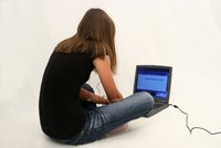 Foto einer jungen Frau, die vor dem Laptop sitzt.